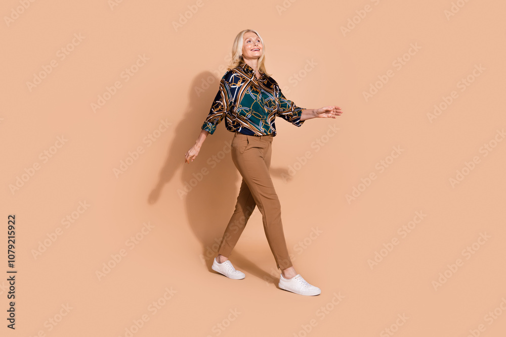 Photo of blonde hair strolling pensioner business lady in glamour formal outfit going looking empty space isolated on beige color background Photo of blonde hair strolling pensioner business lady in glamour formal outfit going looking empty space isolated on beige color background