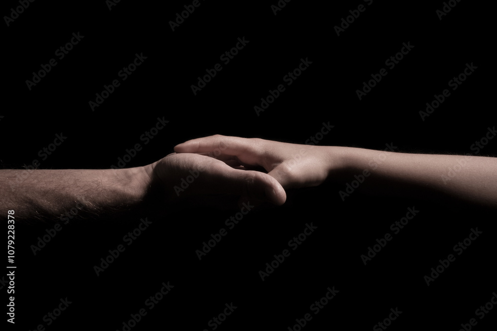 Holding hands over a black background a child and adult hold hands Holding hands over a black background a child and adult hold hands
