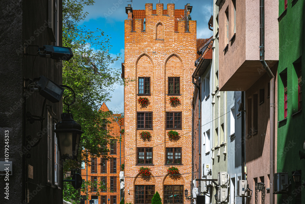 Fototapeta premium Sunlight bathes the historic brick buildings of gdansk, poland, showcasing the city's rich architectural heritage and creating a picturesque scene