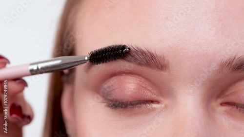 The make-up artist does Long-lasting styling of the eyebrows and will color the eyebrows. Eyebrow lamination. Professional make-up and face care. photo