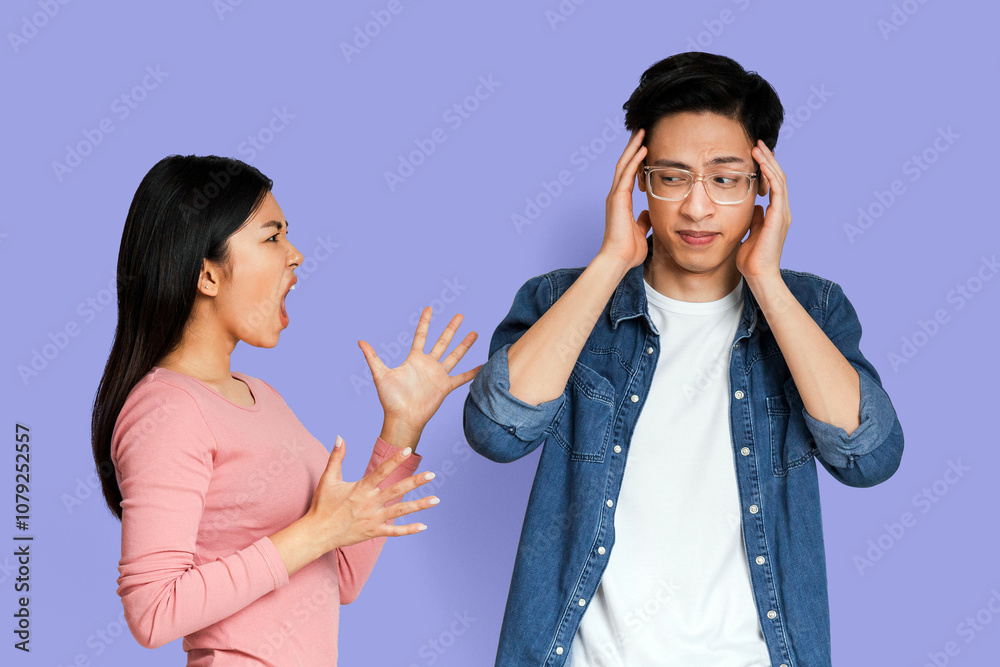 Emotional asian girlfriend shouting at her boyfriend covering ears, grey studio background Emotional asian girlfriend shouting at her boyfriend covering ears, grey studio background