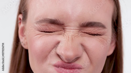 Close-up of a young woman's blue eyes. Her face shows expression lines around her eyes and between her eyebrows.