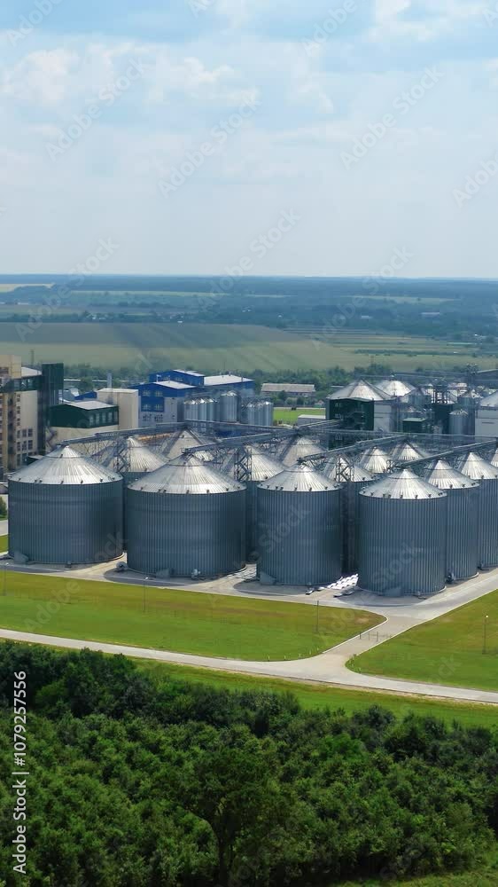 Modern plant on field. Silver silos on agro-processing and manufacturing plant for processing agricultural products. Aerial view. Motion camera back. Vertical video Modern plant on field. Silver silos on agro-processing and manufacturing plant for processing agricultural products. Aerial view. Motion camera back. Vertical video