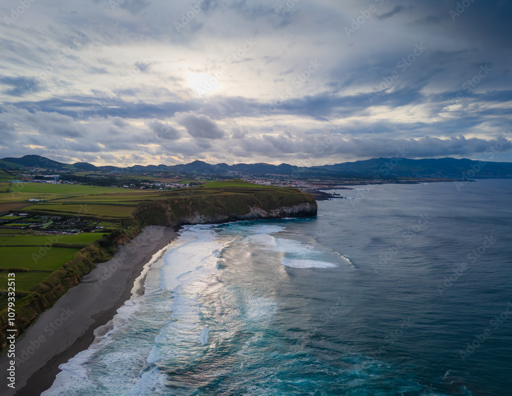 Obraz premium Santa Barbara beach with volcanic sand and turquoise Atlantic ocean waves in Sao Miguel, Azores. Aerial drone view of coast in Ribeira Grande town