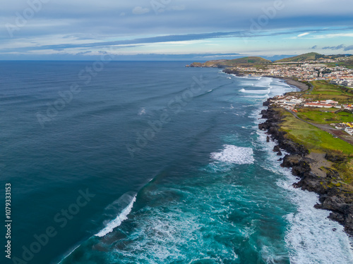 Ribeira Grande on the Atlantic ocean coast in Sao Miguel island, Azores, Portugal. Aerial drone view of city, cliffs and wavy ocean