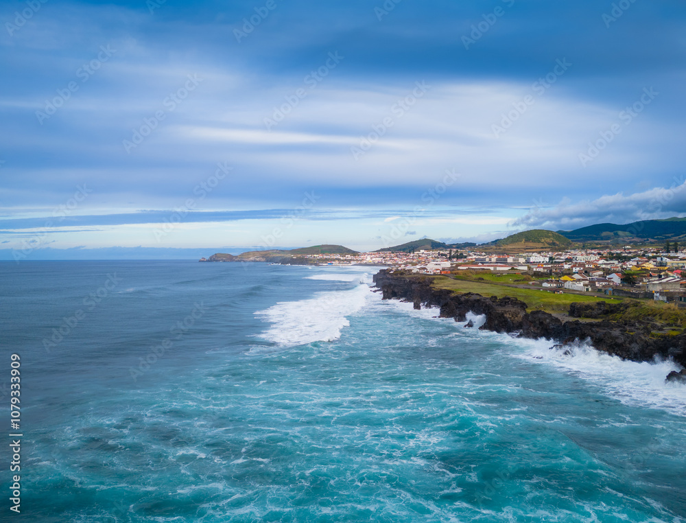Fototapeta premium Ribeira Grande on the Atlantic ocean coast in Sao Miguel island, Azores, Portugal. Aerial drone view of city, cliffs and wavy ocean