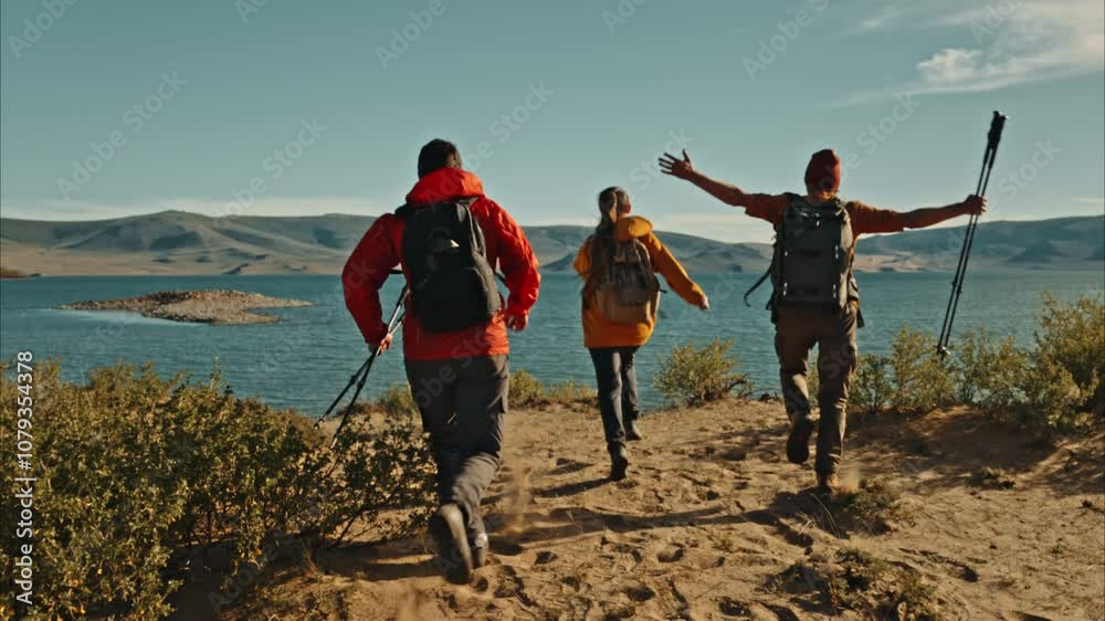 Three hikers with backpacks walks at the sandy lake beach at sunset time Three hikers with backpacks walks at the sandy lake beach at sunset time