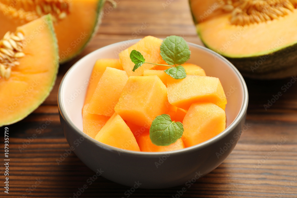 Pieces of Cantaloupe melon and mint in bowl on wooden table, closeup Pieces of Cantaloupe melon and mint in bowl on wooden table, closeup