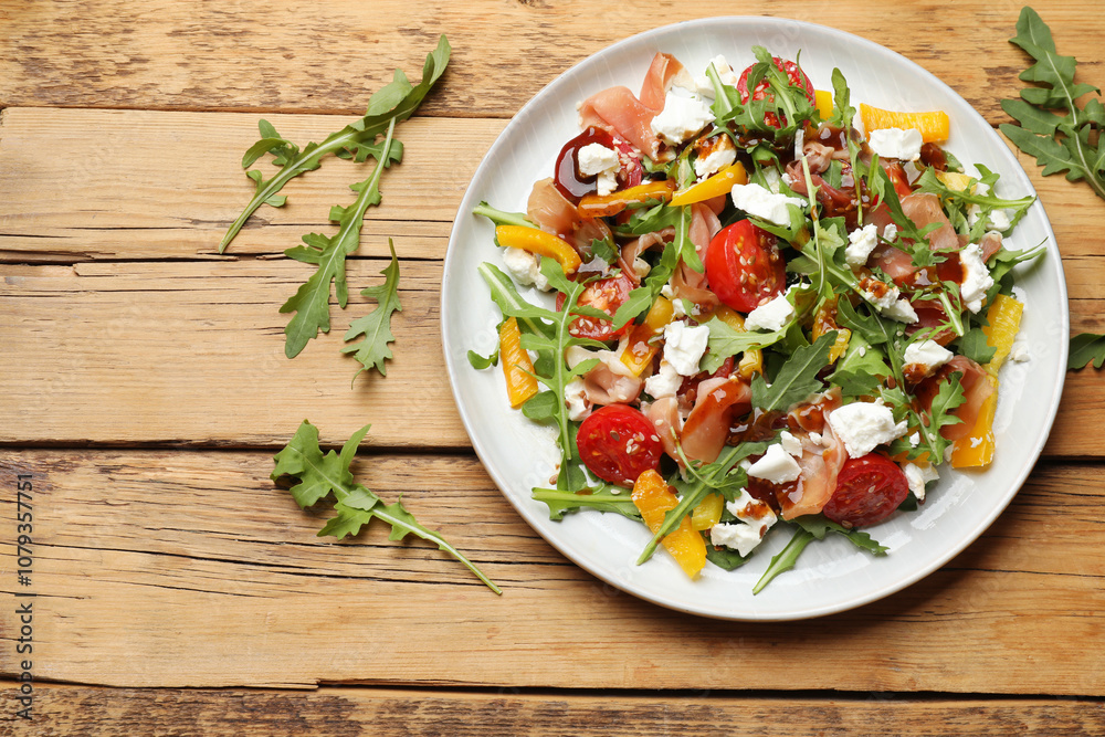Tasty salad with arugula, cheese and vegetables on wooden table, flat lay. Space for text Tasty salad with arugula, cheese and vegetables on wooden table, flat lay. Space for text