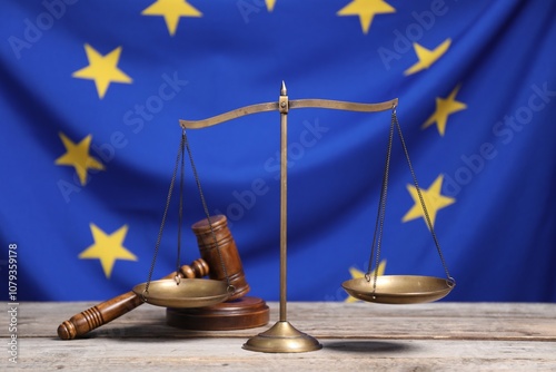 Scales of justice and judge's gavel on wooden table against European Union flag photo