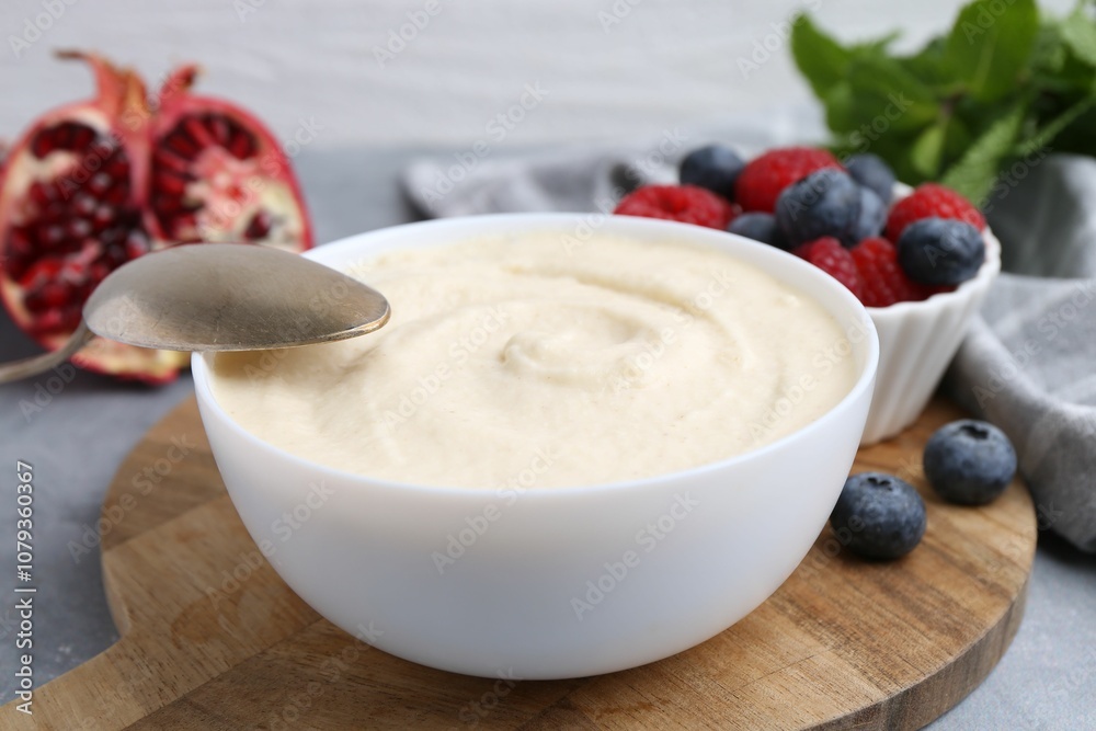 Tasty cooked semolina porridge in bowl and berries on grey table, closeup Tasty cooked semolina porridge in bowl and berries on grey table, closeup