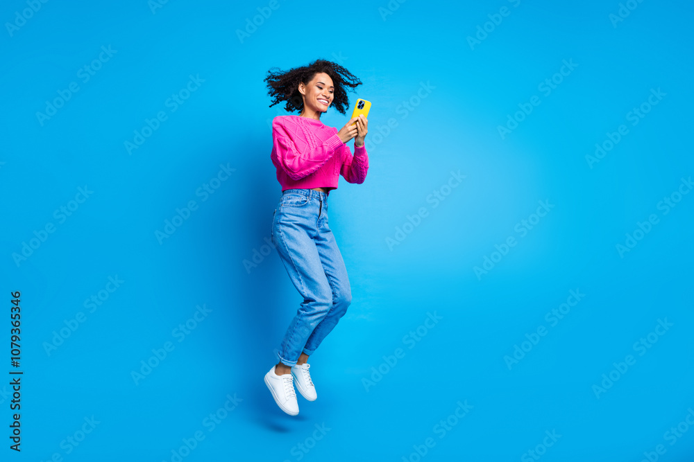 Full size photo of pretty young girl jump hold gadget wear trendy pink outfit isolated on blue color background