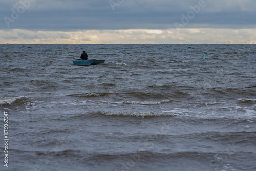 The fisherman checks the nets at sea. A small boat in big waves. Safety on water. photo