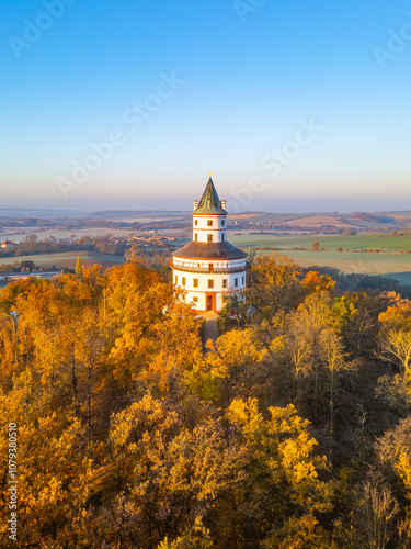 The Baroque hunting chateau Humprecht rises amidst vibrant autumn foliage, basking in the golden hues of sunrise over the Bohemian Paradise, above Sobotka in Czechia. photo