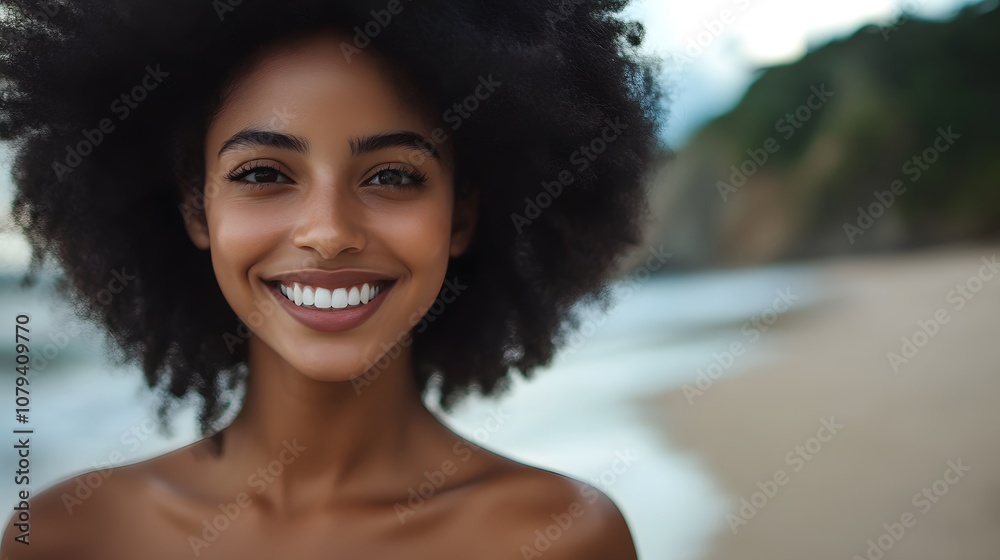 Fototapeta premium A woman with an afro smiling at the camera on a beach