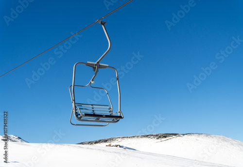 An empty chairlift suspended over a snowy landscape, capturing the peacefulness of a winter day in the mountains, with untouched snow below. photo