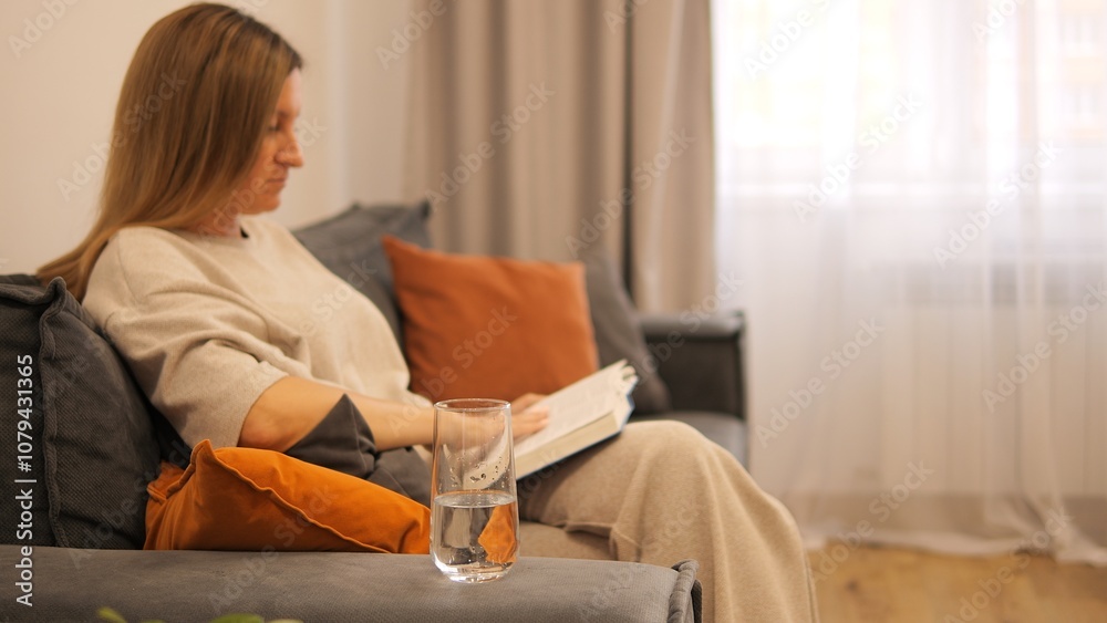 A woman sits on a sofa, deeply immersed in a book. The book provides, offering peaceful enjoyment. Perfect for literary themes, cozy moments of reading, and the simple pleasure of a good book. A woman sits on a sofa, deeply immersed in a book. The book provides, offering peaceful enjoyment. Perfect for literary themes, cozy moments of reading, and the simple pleasure of a good book.