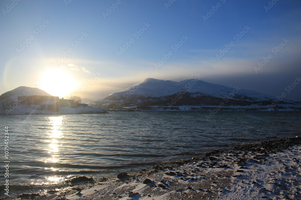 Fototapeta premium Winter landscapes in Norway showcase serene snowy mountains, icy fjords, and peaceful coastal views. Capturing the beauty of snow-covered trees, quiet roads, and glowing sunsets creates a sense of cal