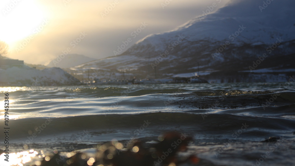 Fototapeta premium Winter landscapes in Norway showcase serene snowy mountains, icy fjords, and peaceful coastal views. Capturing the beauty of snow-covered trees, quiet roads, and glowing sunsets creates a sense of cal