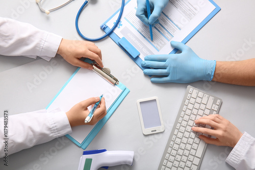 Doctor's hands with clipboard, medical insurance and computer keyboard on whi...