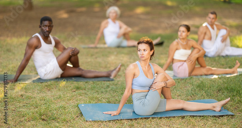 Various yoga poses performed by group of multinational people in the fresh air in the summer garden photo