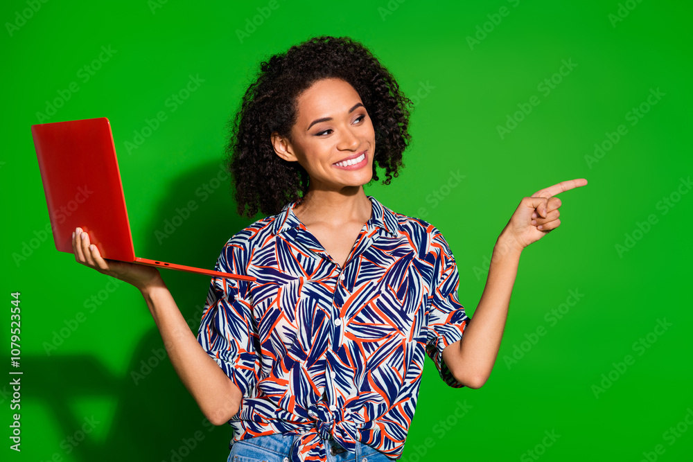 Photo portrait of pretty young girl hold netbook point empty space wear trendy colorful outfit isolated on green color background Photo portrait of pretty young girl hold netbook point empty space wear trendy colorful outfit isolated on green color background