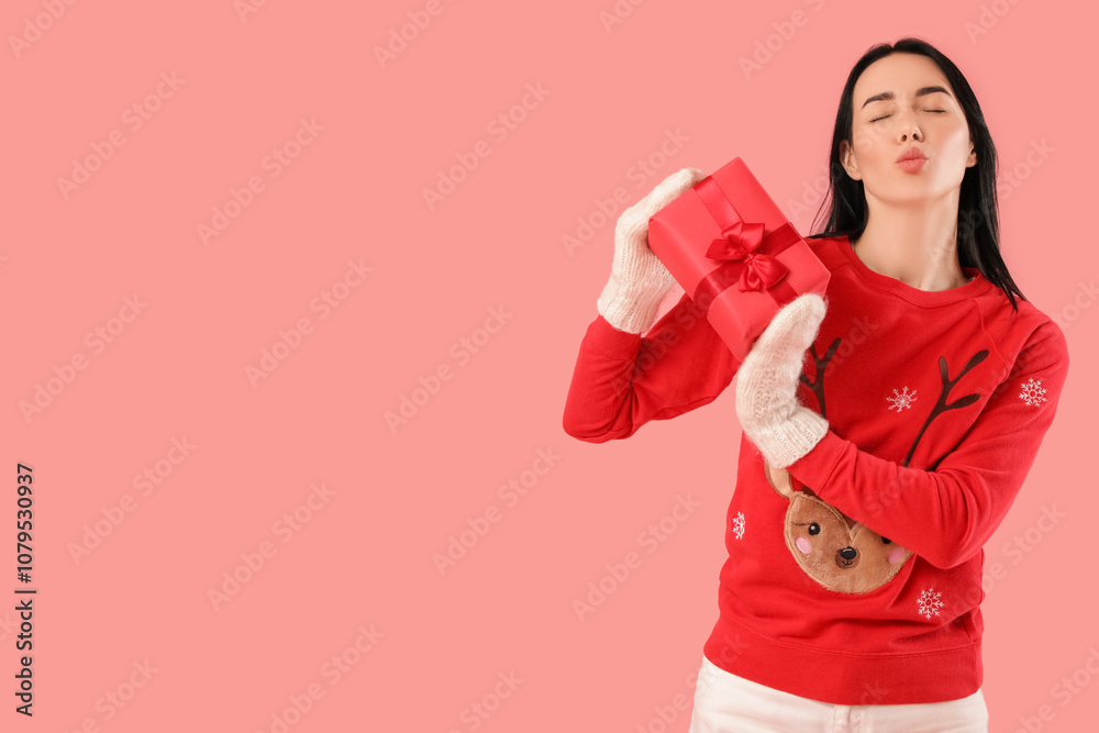 Pretty young woman with Christmas gift box blowing kiss on pink background Pretty young woman with Christmas gift box blowing kiss on pink background