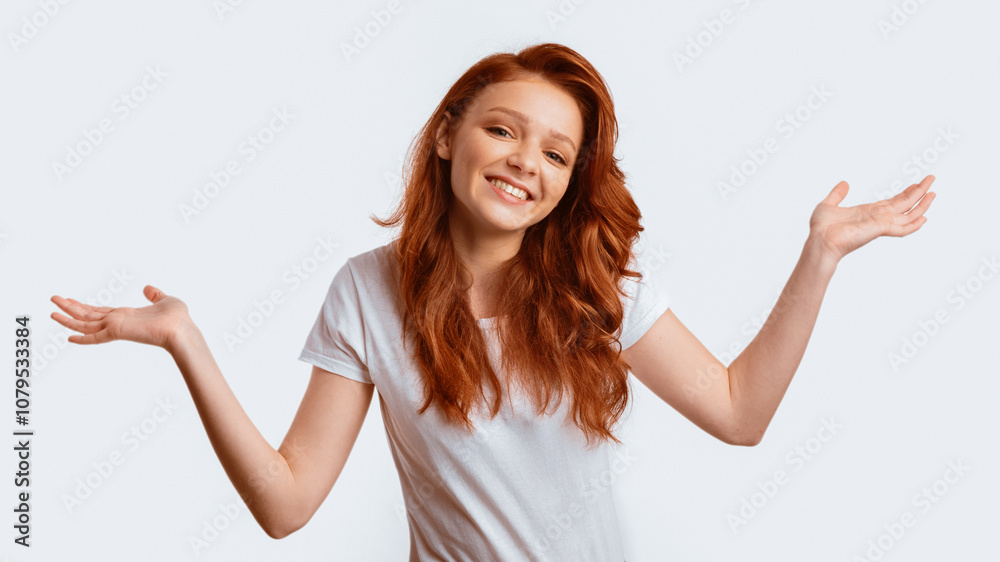 Carefree Ginger-Haired Girl Shrugging Shoulders Smiling To Camera Posing Over White Studio Background. Panorama Carefree Ginger-Haired Girl Shrugging Shoulders Smiling To Camera Posing Over White Studio Background. Panorama