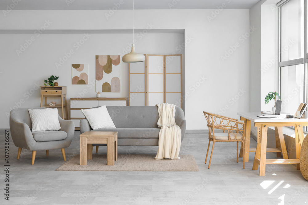 Fototapeta premium Interior of light living room with workplace, sofa and armchair