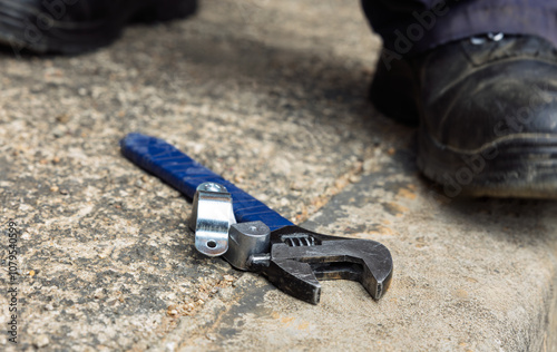 Adjustable Wrench spanner, worker safety shoes on the ground photo