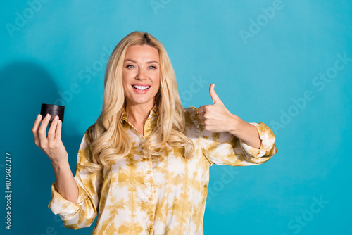 Photo portrait of stunning mature lady hold cream thumb up dressed stylish formalwear clothes isolated on cyan color background photo