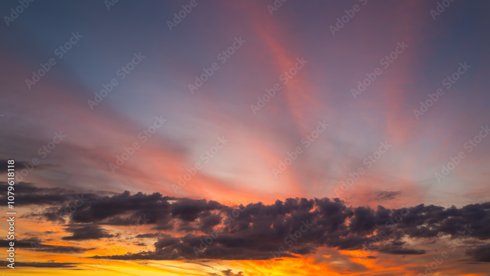 Fototapeta premium Sunset background. Dramatic majestic scenery sunset. Sky with clouds in sunset sky light background. Sunrise with clouds in various shapes. Calm sunset sky and sun through clouds over.
