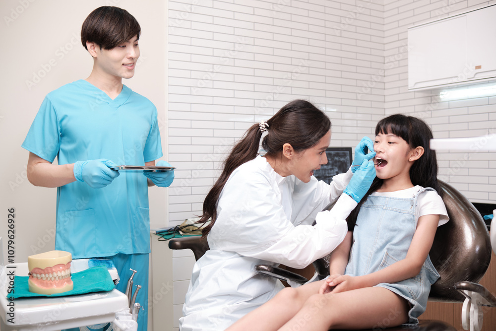Asian female pediatric dentist and assistant check and examination a little girl's caries teeth in dental clinic, well-being hygiene, and professional orthodontic healthcare work in kid hospital. Asian female pediatric dentist and assistant check and examination a little girl's caries teeth in dental clinic, well-being hygiene, and professional orthodontic healthcare work in kid hospital.