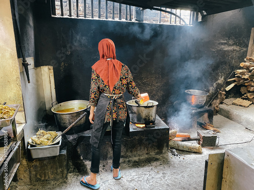 A woman cooking with firewood in traditional kitchen in Semarang, Indonesia photo