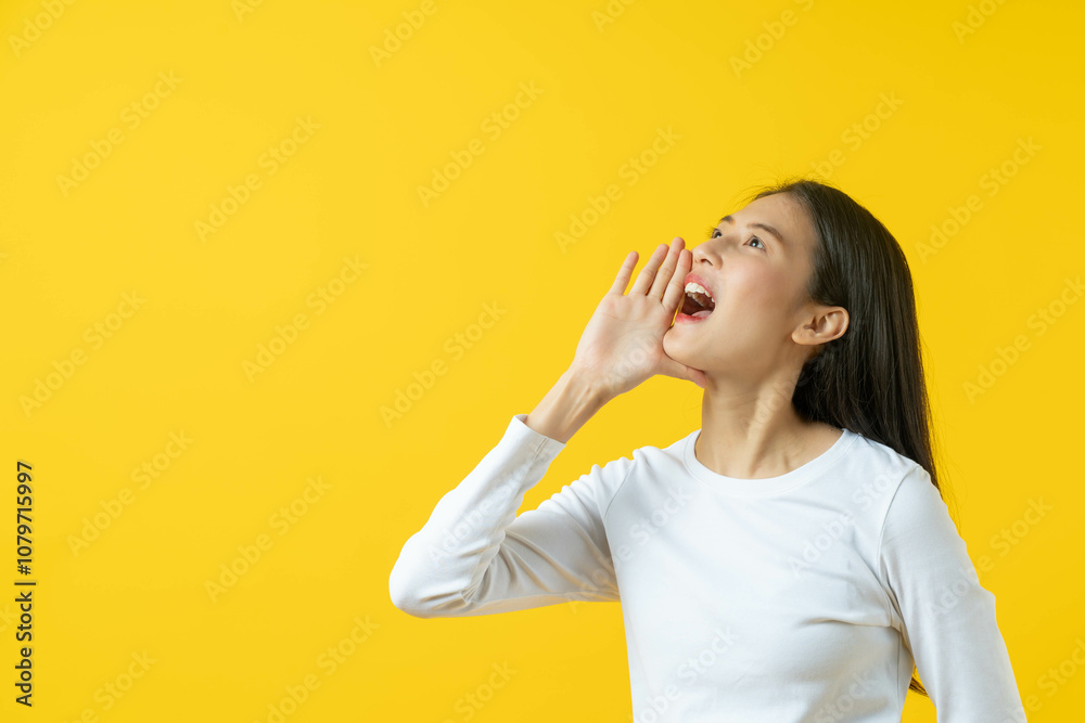 asian teenager in white casual shirt shouting news isolated on yellow background in studio. asian teenager in white casual shirt shouting news isolated on yellow background in studio.