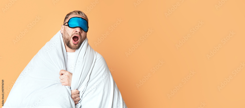 Guy in mask for sleep yawns wrapped in blanket, free space Guy in mask for sleep yawns wrapped in blanket, free space