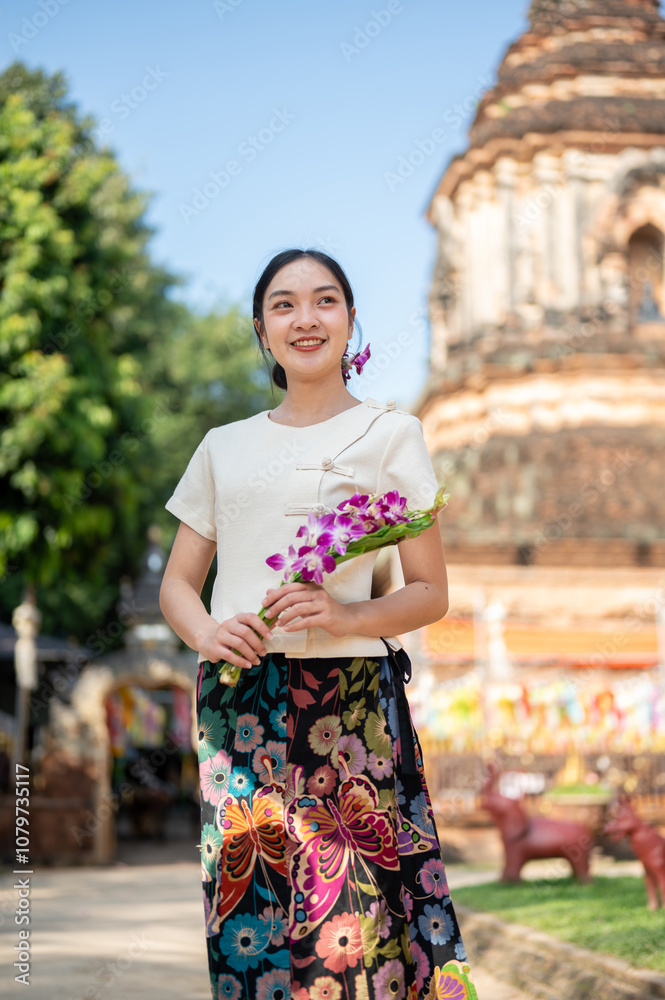 A charming Asian woman in a traditional Thai Lanna dress with a temple in the background. A charming Asian woman in a traditional Thai Lanna dress with a temple in the background.
