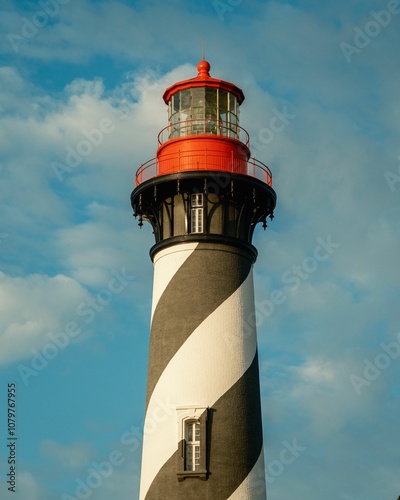 A towering black and white striped lighthouse with a red top against a blue sky, located at the St. Augustine Lighthouse & Maritime Museum, St. Augustine, Florida.