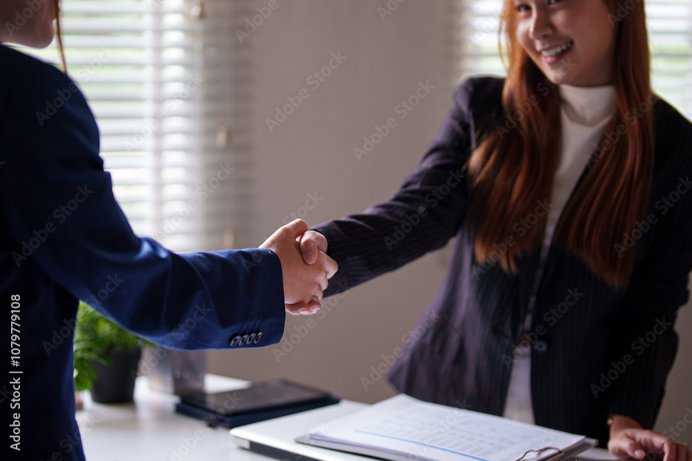 wo professional women in an office shake hands across a desk, smiling in agreement and signaling successful collaboration or deal closure in a bright, organized workspace wo professional women in an office shake hands across a desk, smiling in agreement and signaling successful collaboration or deal closure in a bright, organized workspace