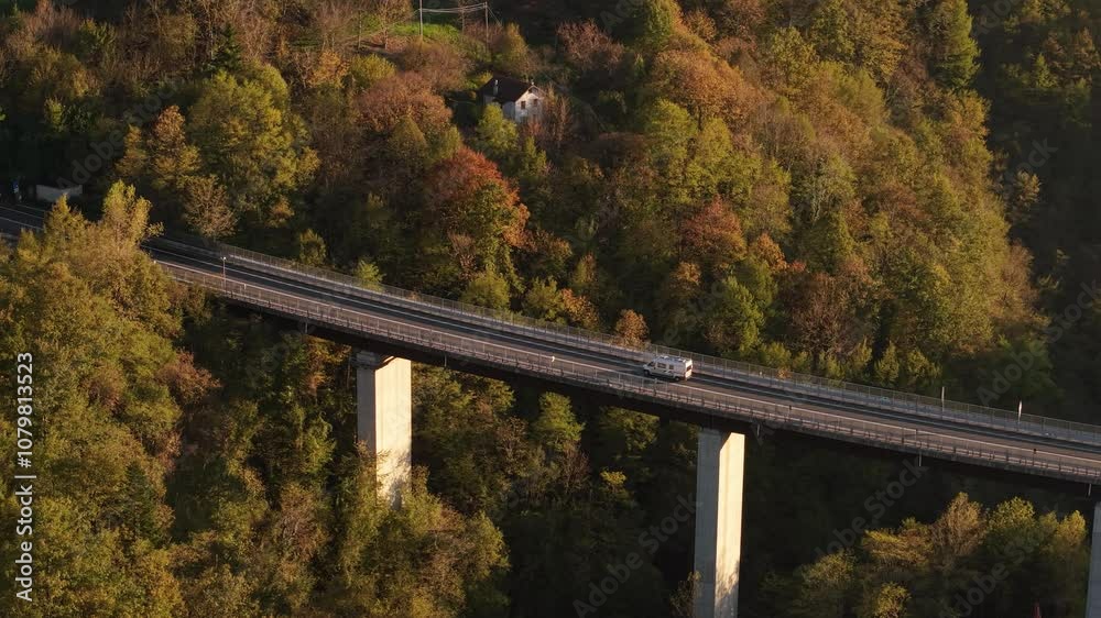 A train travels across a bridge surrounded by vibrant autumn foliage in Italy at sunset A train travels across a bridge surrounded by vibrant autumn foliage in Italy at sunset
