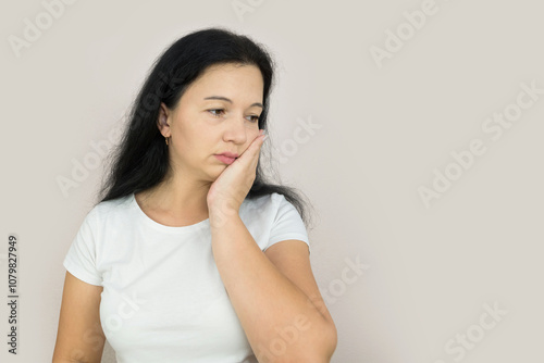 Beautiful young woman suffering from toothache on gray background