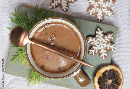 Cozy winter lifestyle concept. Mug of hot drink with vintage book and tasty homemade Christmas gingerbread cookies.	