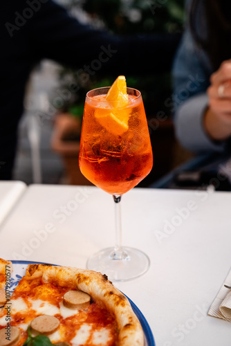 Close-up of a refreshing Aperol Spritz cocktail served in a chilled wine glass, garnished with a slice of orange, creating a vibrant, inviting color