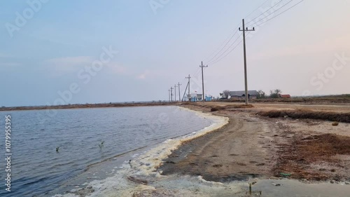 Small waves wave in pond with electric poles on the edge with blue sky in Pamekasan, Indonesia photo