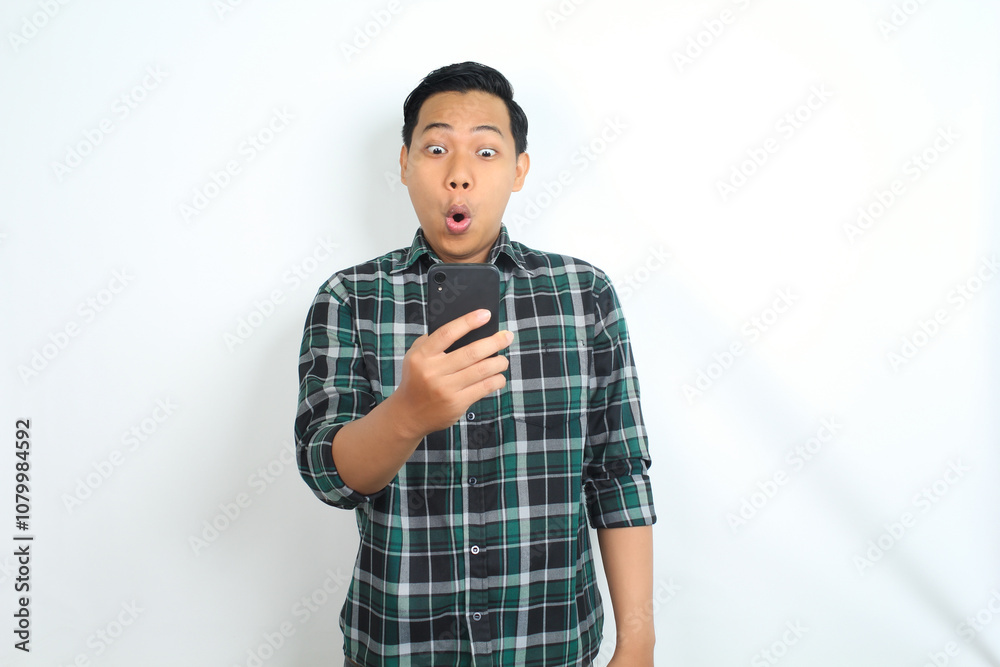surprised asian man looking at smartphone with shocked face, wow expression, isolated on white background surprised asian man looking at smartphone with shocked face, wow expression, isolated on white background