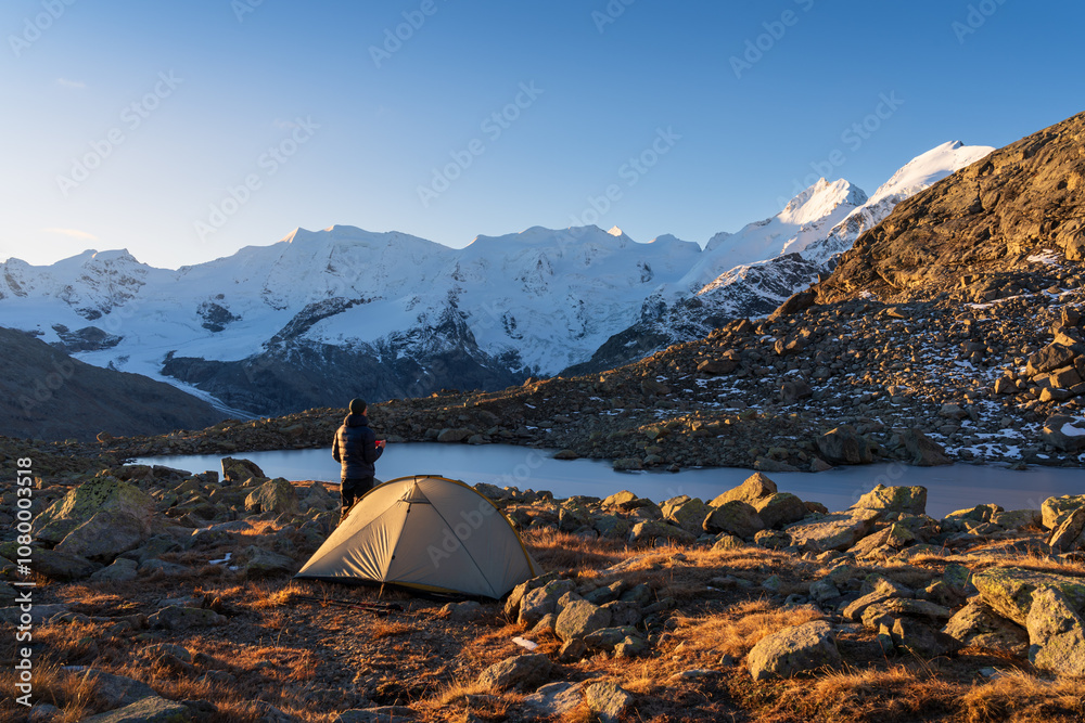 A hiker enjoying his coffee at a beautiful campsite in the Bernina mountain range. Switserland.