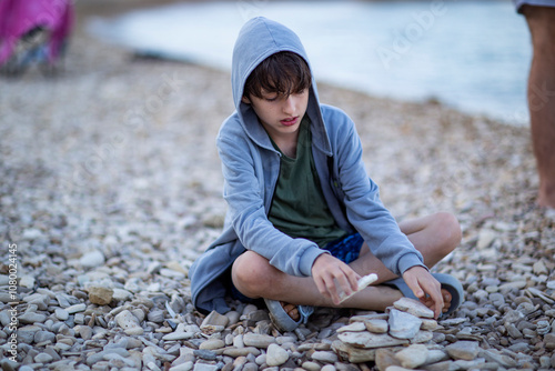 Cute boy stacking stones by the sea photo