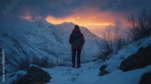 A lone hiker pauses in the snowy mountains at dusk, facing a colorful sky. photo