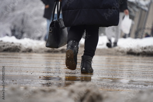 People walk through the wet dirty snow on the street. photo