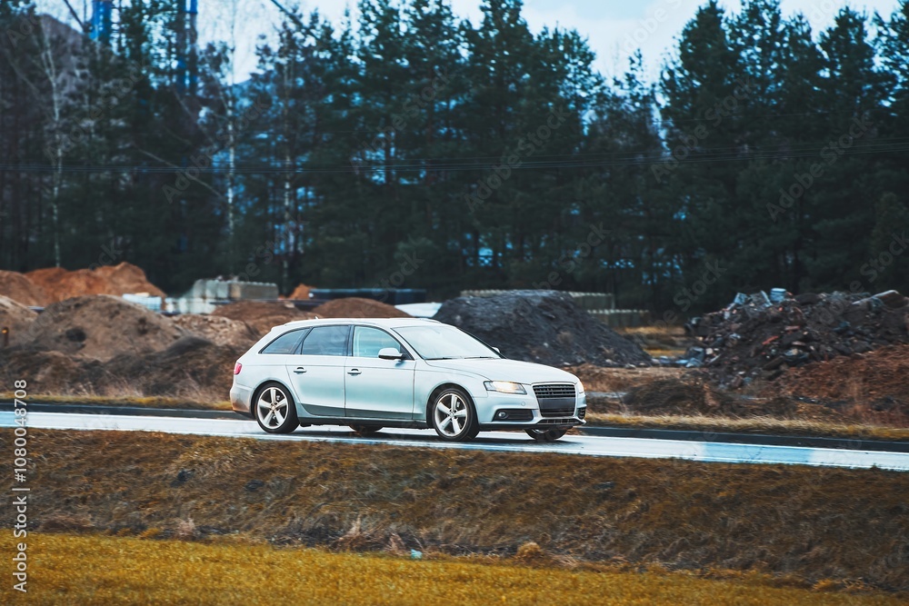 SUV on rainy countryside drive with green and dirt hills SUV on rainy countryside drive with green and dirt hills